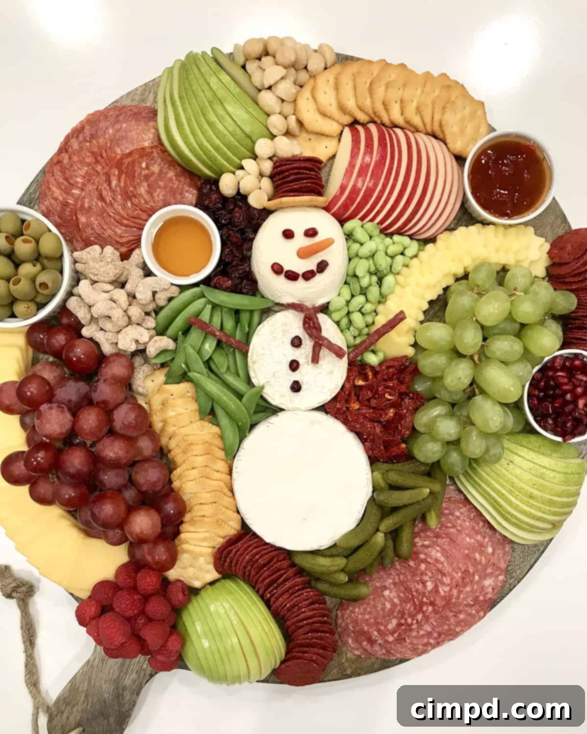 A delightful Snowman Snack Board, designed by The BakerMama, showcasing a variety of festive red, green, and white snacks.