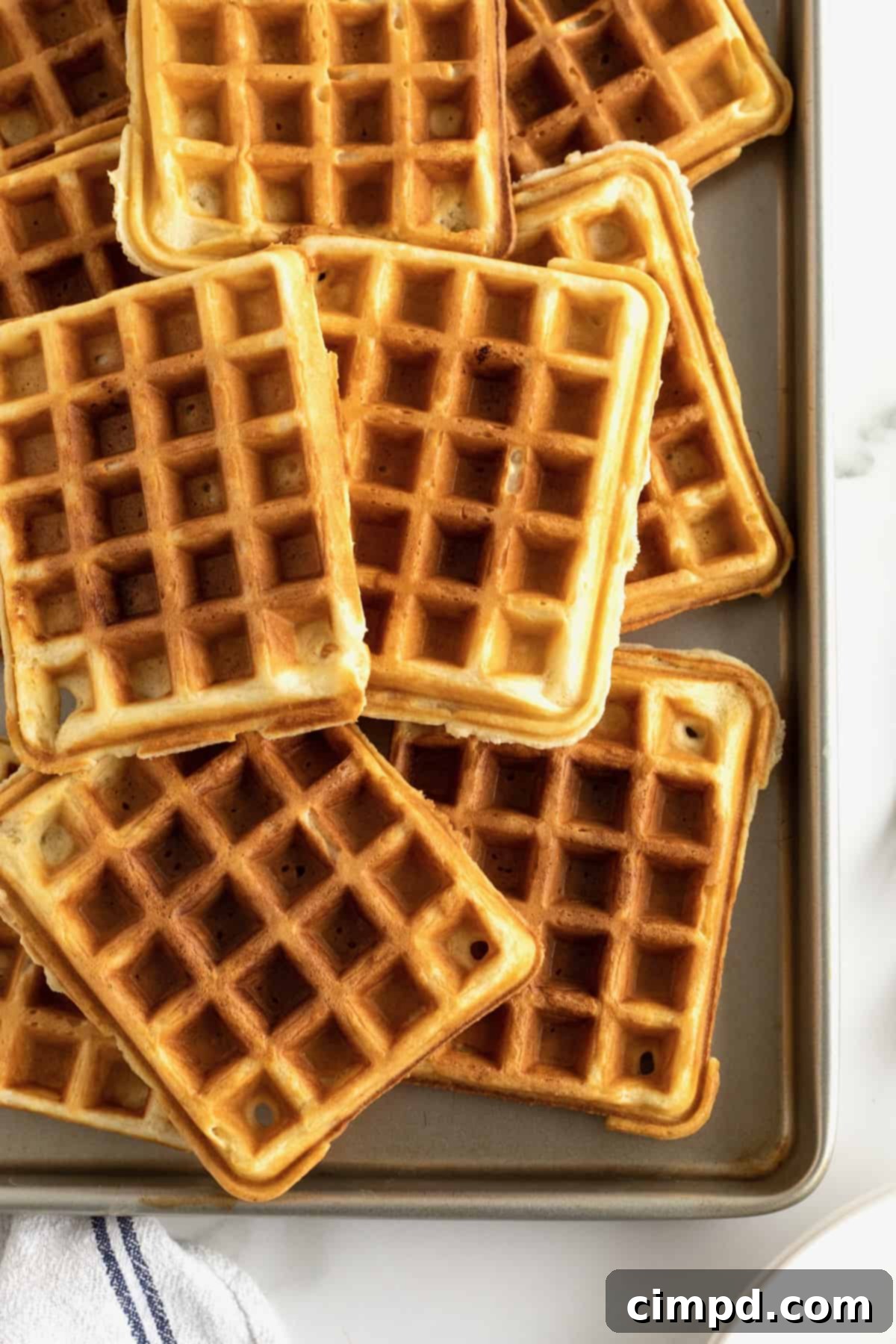An aluminum sheet pan filled with crispy waffles.