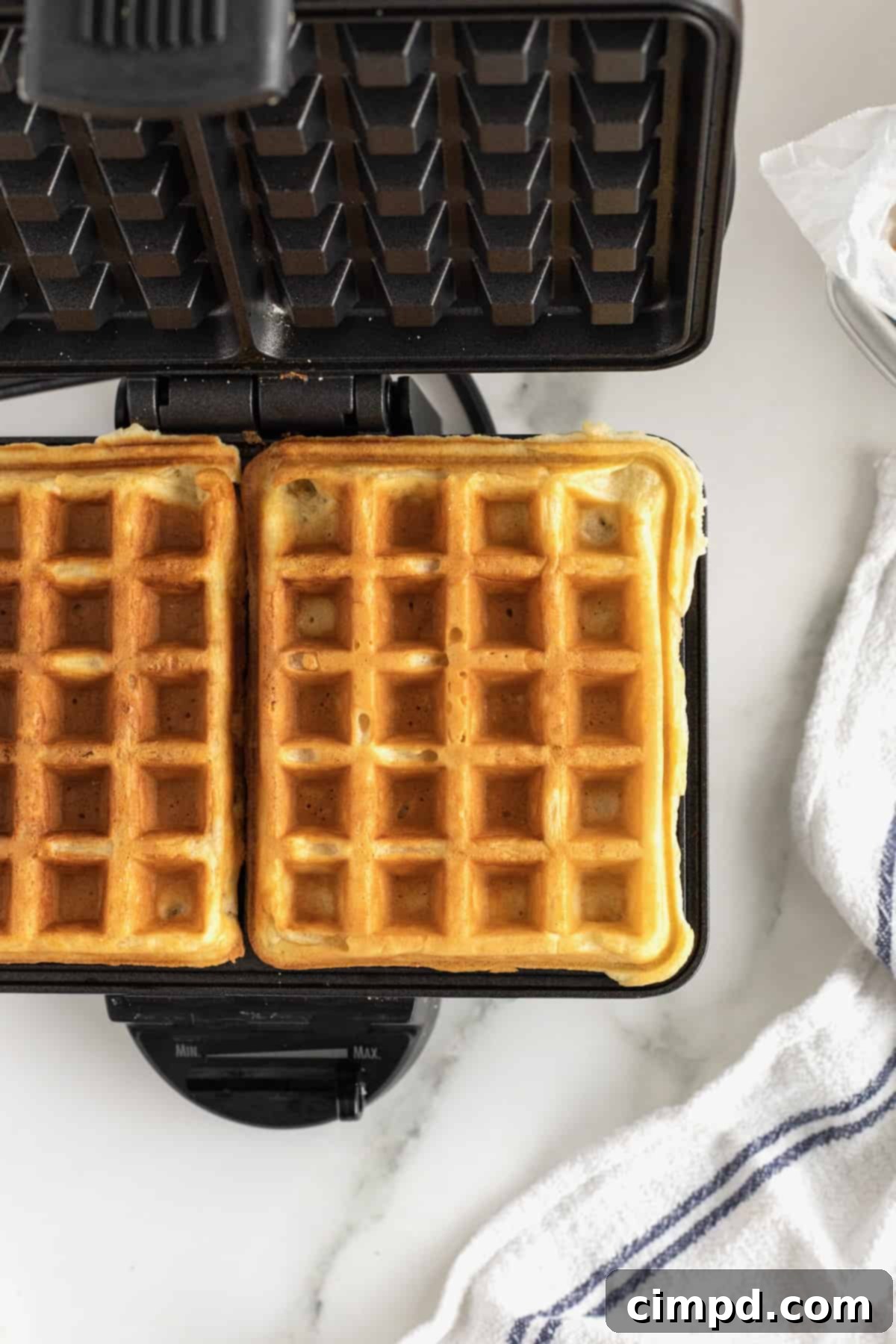 Two waffles side by side in a waffle maker.