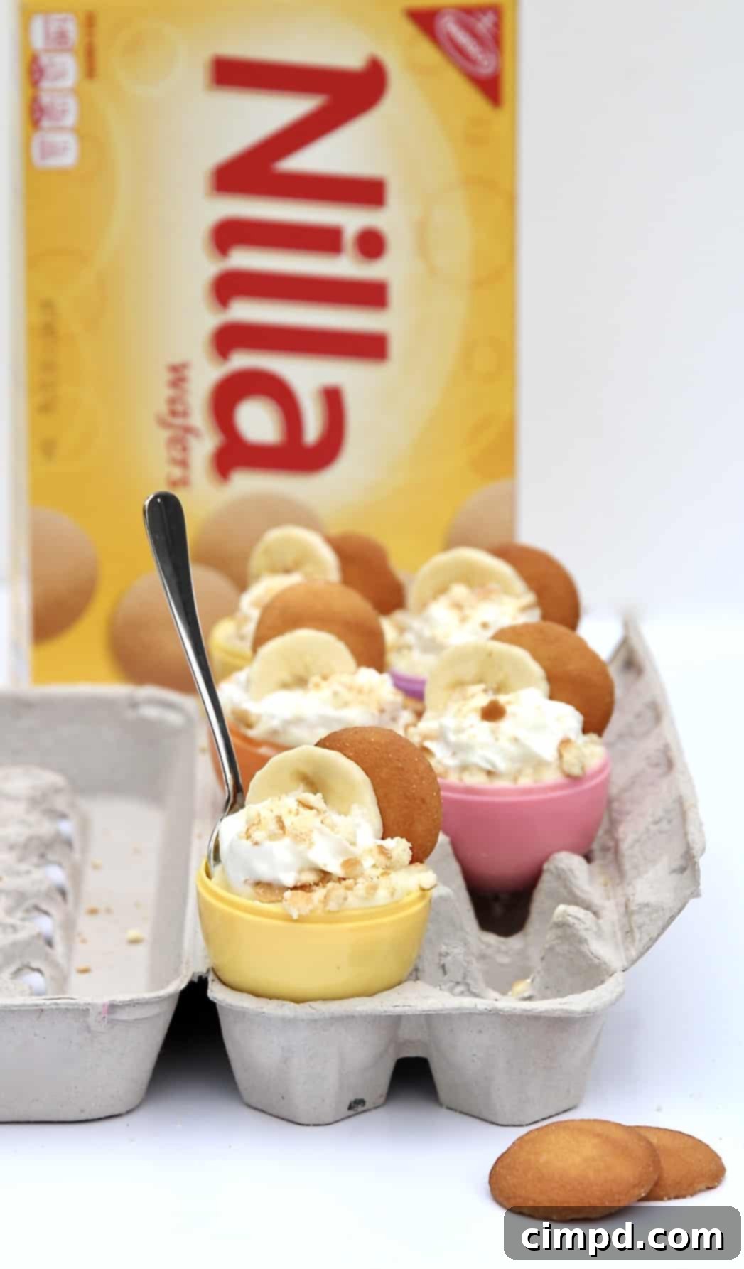 Close-up of an Easter Egg Banana Pudding Cup, showcasing layers of vanilla wafers, sliced bananas, and creamy pudding topped with whipped cream and a wafer.