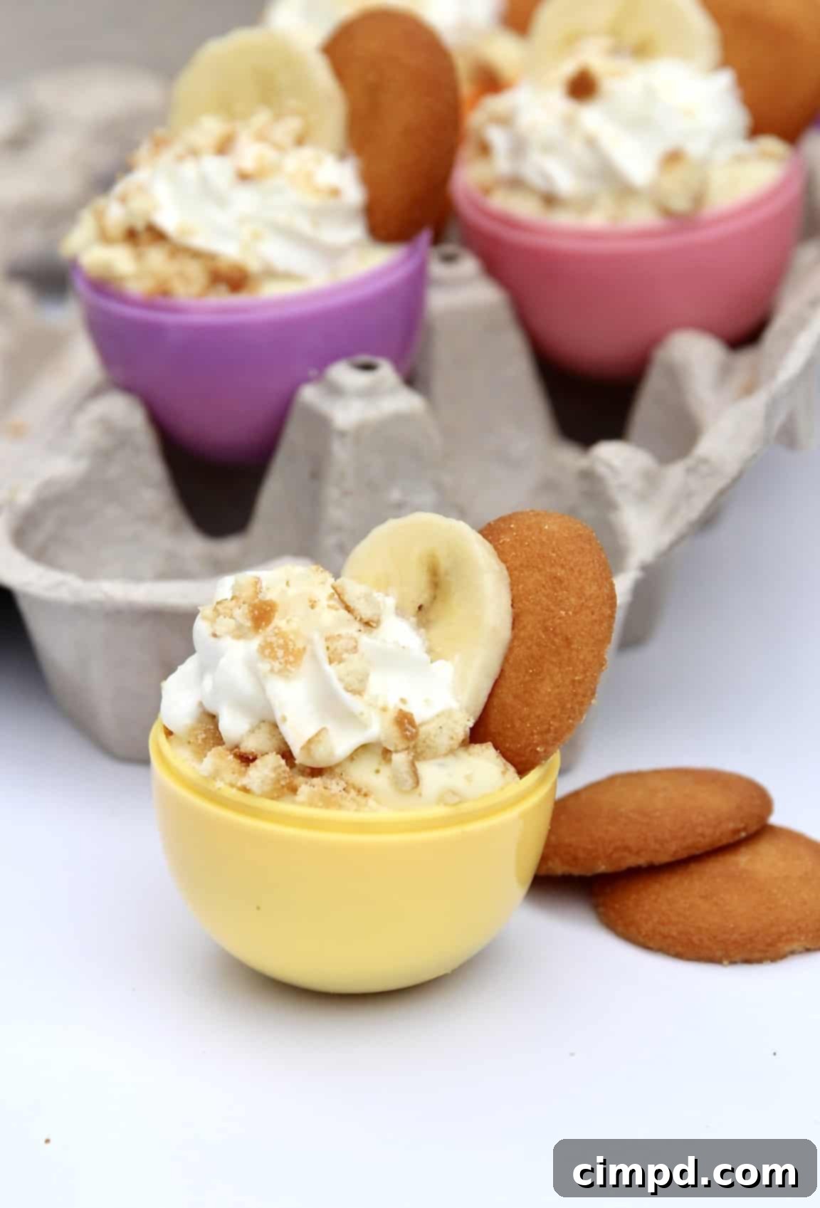 Ingredients laid out for Easter Egg Banana Pudding Cups, including vanilla wafers, bananas, and a bowl of pudding, all ready for assembly.