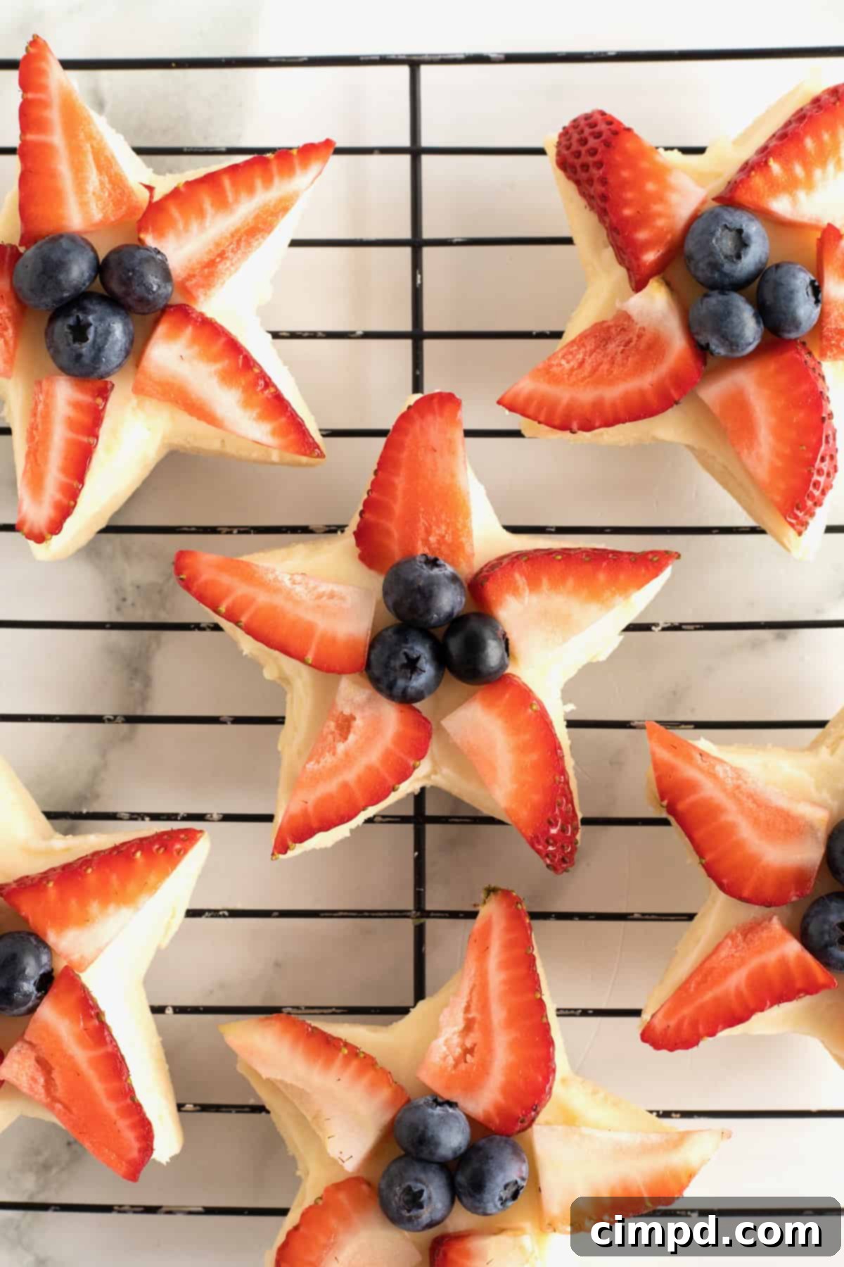Star-shaped shortbread cookies topped with fresh strawberry slices and blueberries, a festive treat.
