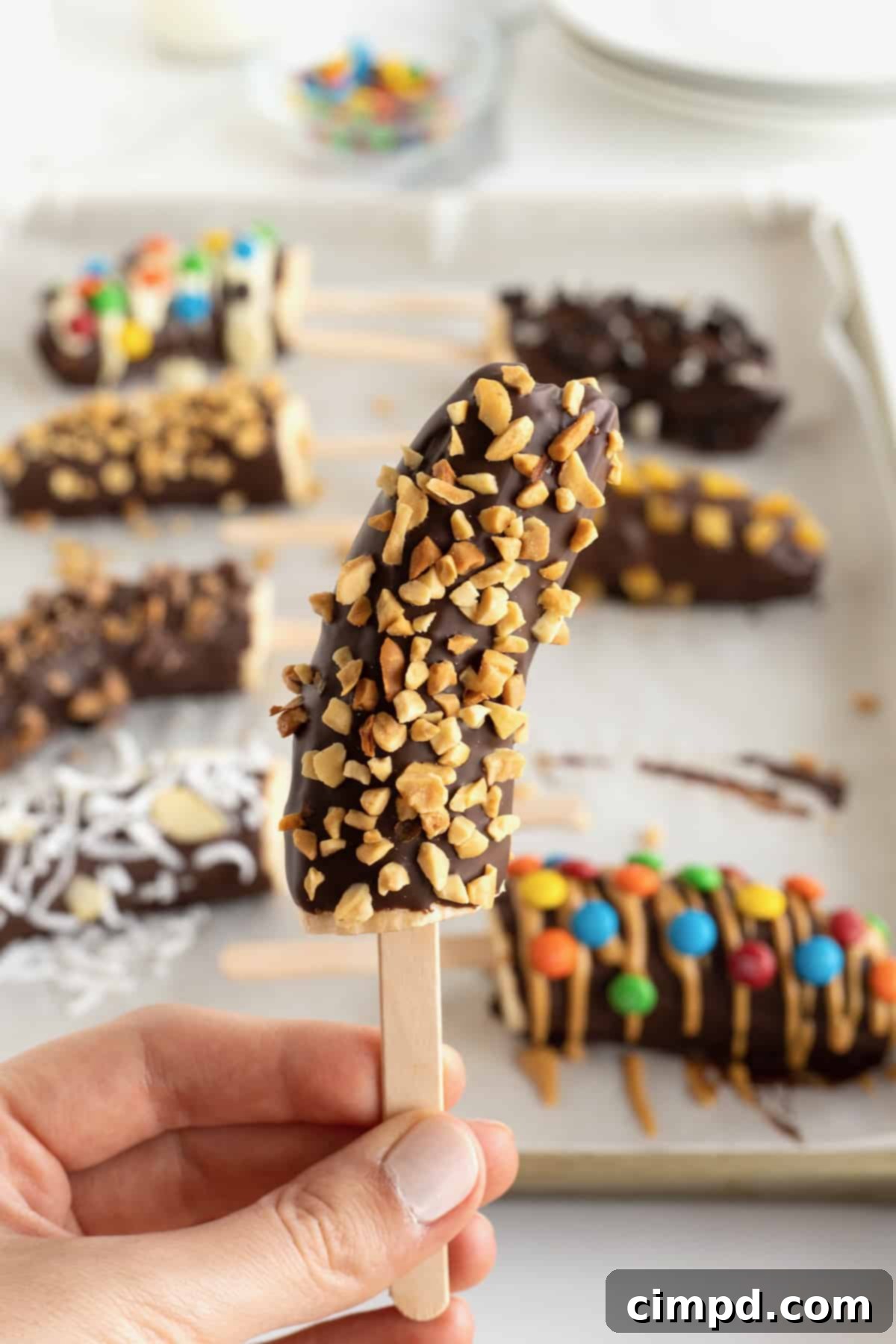 A frozen banana on a popsicle stick covered in chocolate and crushed peanuts.