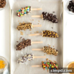 Frozen bananas with popsicle sticks covered in chocolate and mini M&Ms, mini chocolate chips, crushed peanuts and coconut.