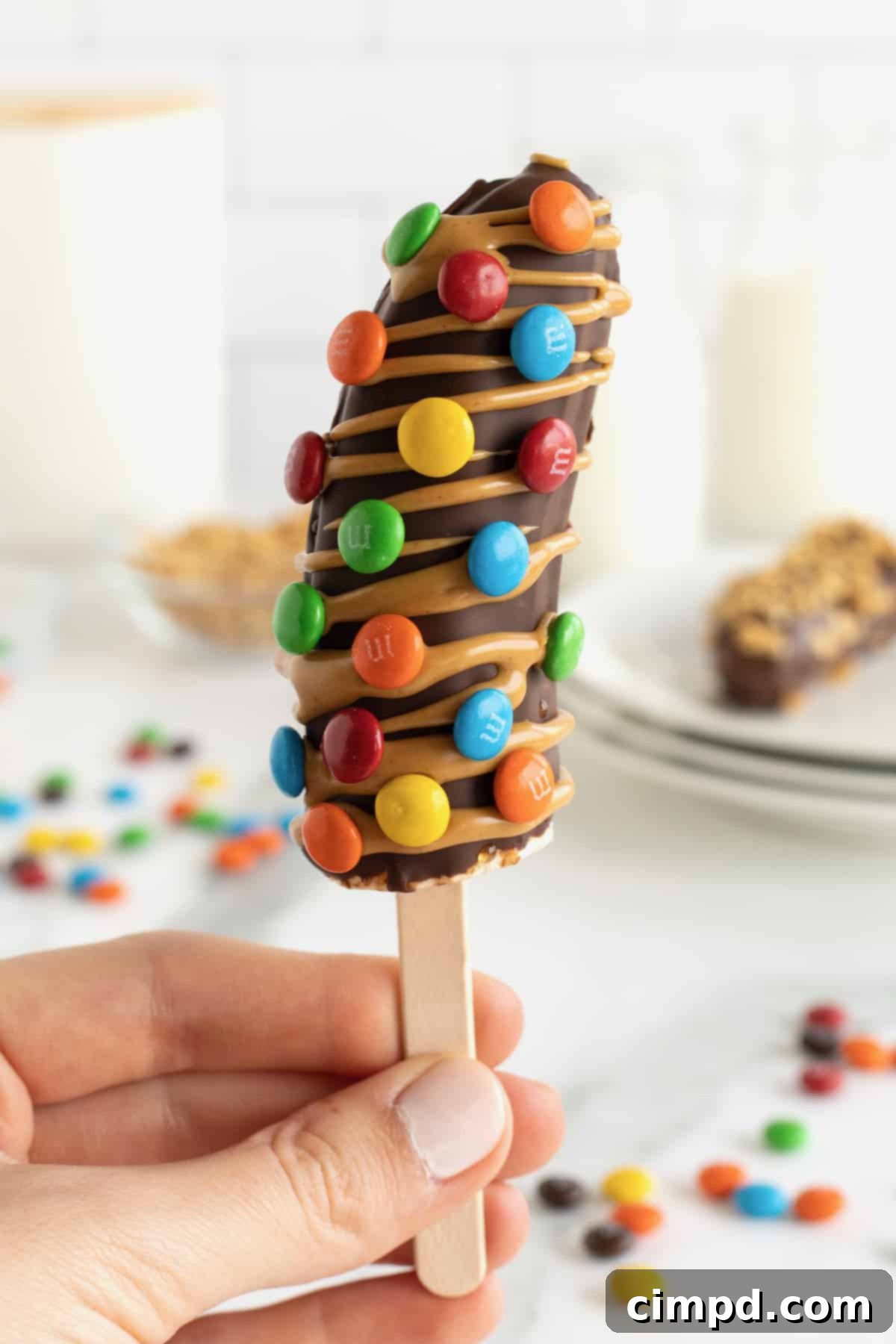 A frozen banana on a popsicle stick, dipped in chocolate, coated in M&Ms and drizzled with melted peanut butter.