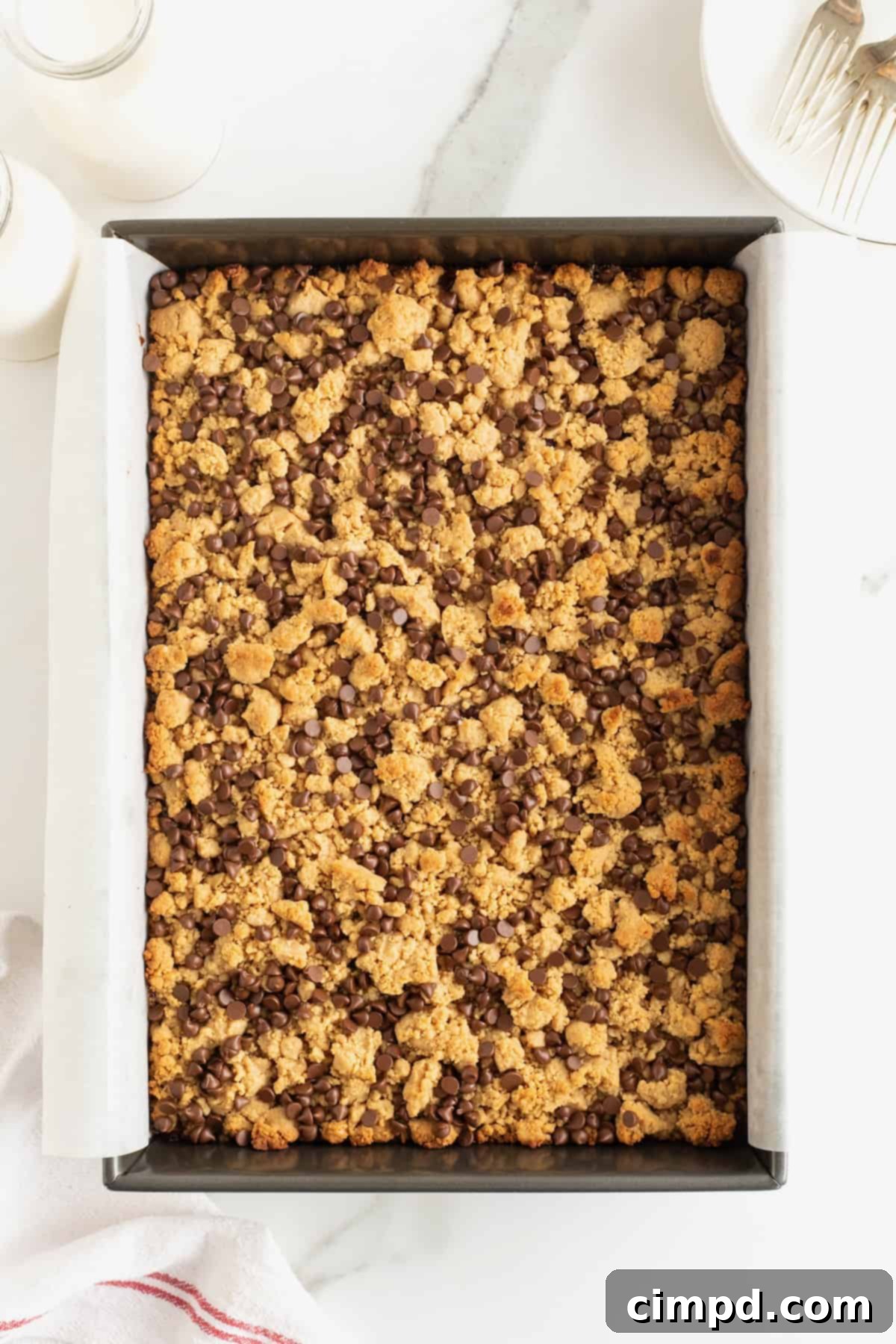 Peanut butter and jelly bars in a parchment lined aluminum baking pan.