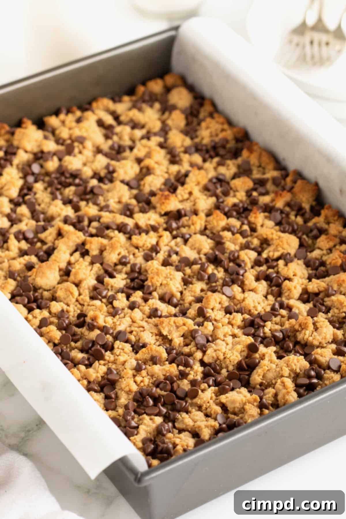A parchment lined aluminum baking dish with peanut butter and jelly bars inside.