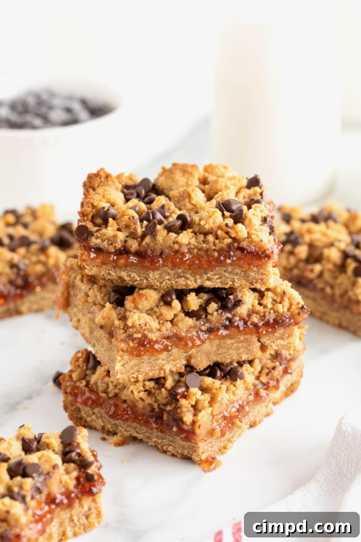 A stack of three peanut butter and jelly bars on a white plate.