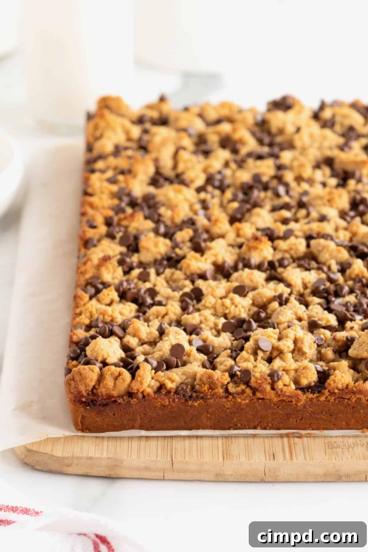 Peanut Butter and Jelly Bars uncut on a piece of parchment on a cutting board.
