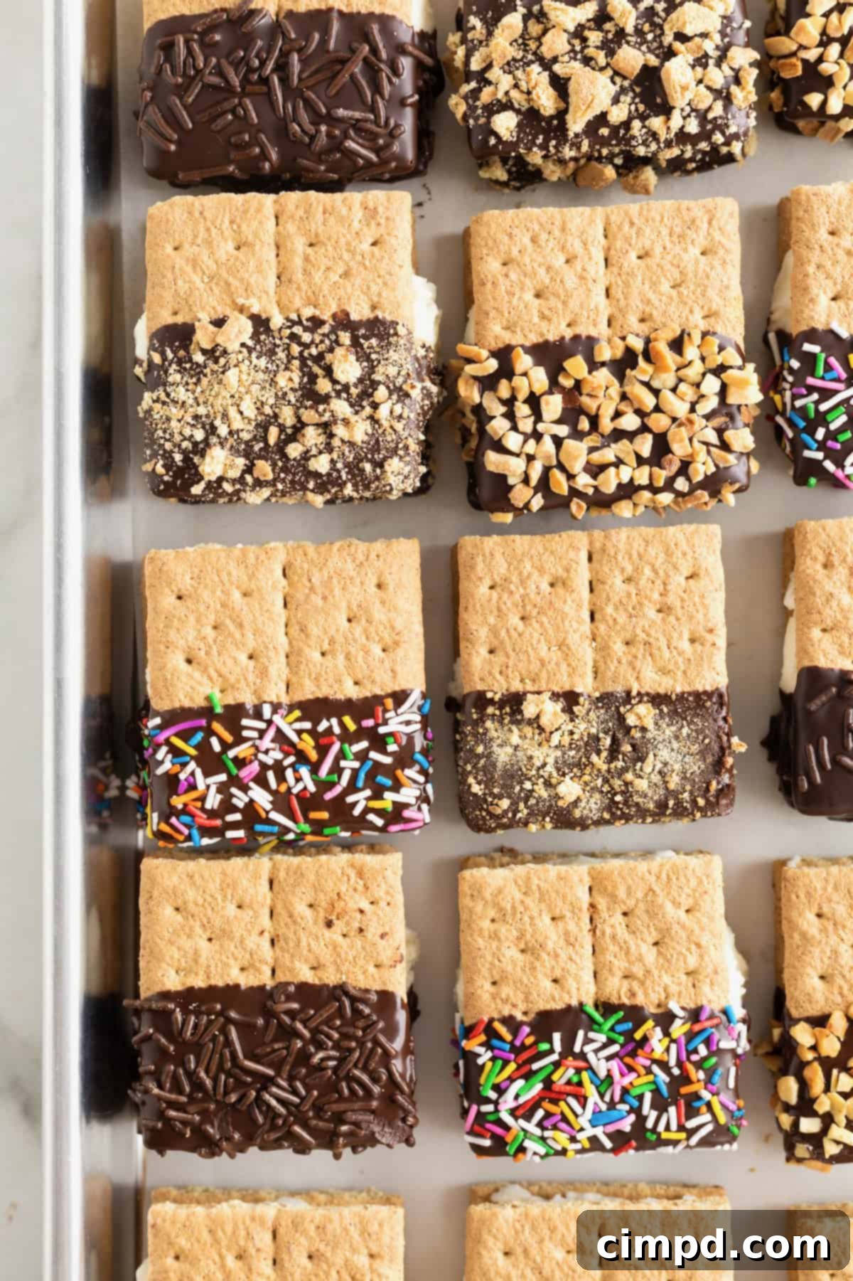 Six graham cracker ice cream sandwiches on a parchment lined baking sheet.