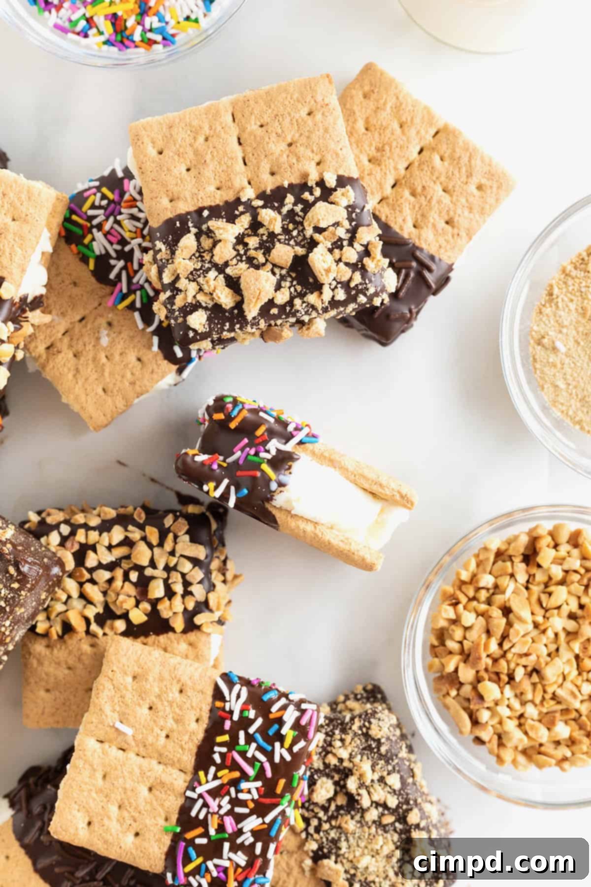 Chocolate-dipped graham cracker ice cream sandwiches on a white counter.