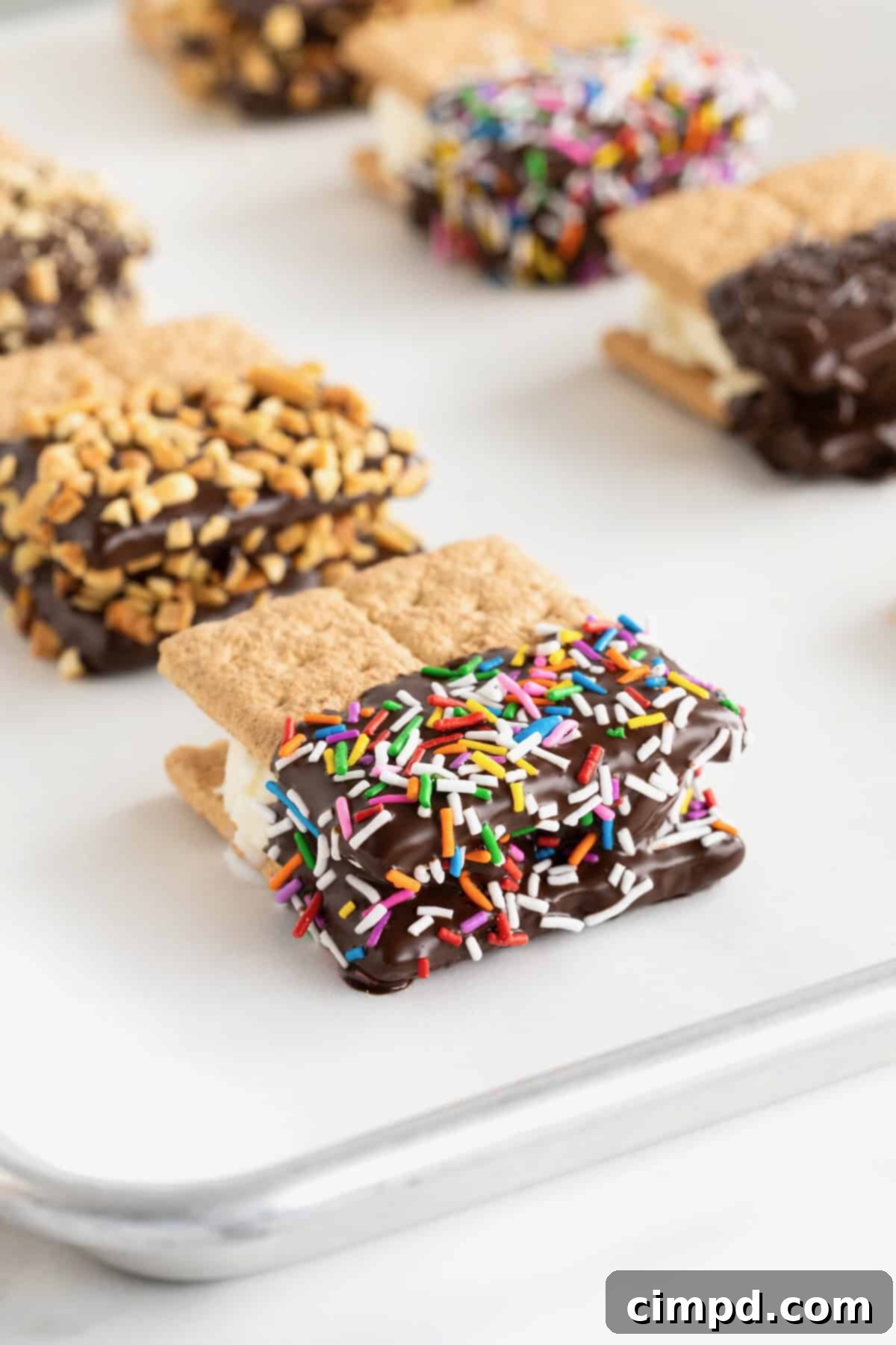 Six graham cracker ice cream sandwiches on a parchment lined baking sheet.