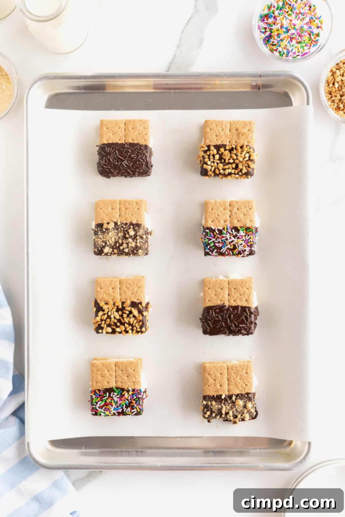 Eight graham cracker ice cream sandwiches on a parchment lined baking sheet.