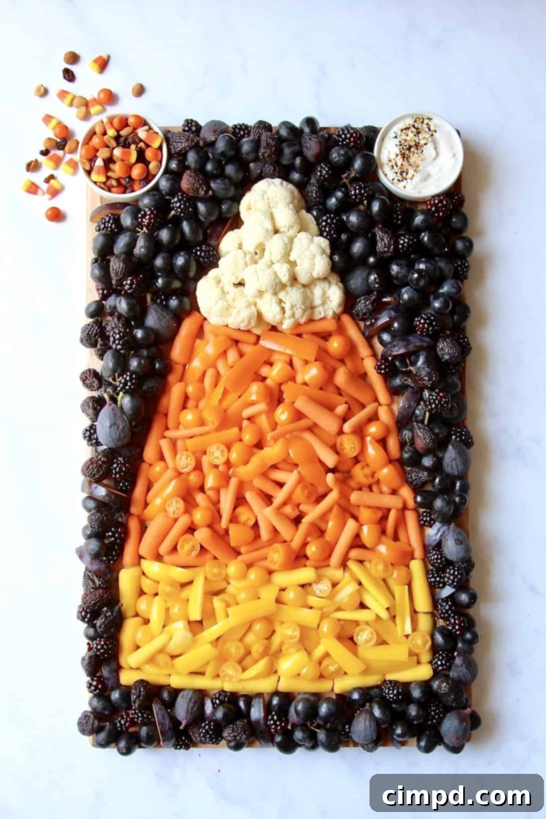 Vibrant Candy Corn Snack Board featuring healthy fruits and vegetables arranged in candy corn colors for Halloween parties.