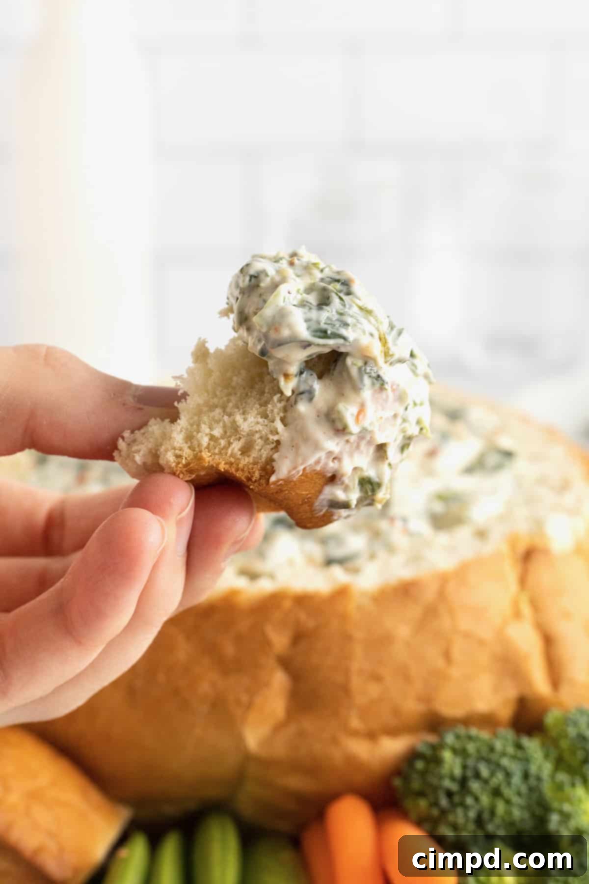 A close-up shot of a bread chunk generously coated with creamy spinach dip, ready to be enjoyed.