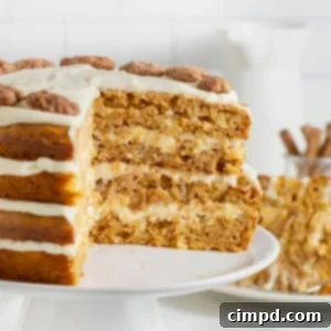 A layered pumpkin pineapple cake on a white cake stand. A large wedge is cut out of the cake to reveal the inside layers.