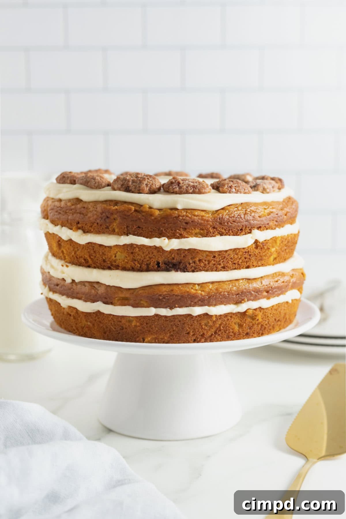 A stunning multi-layered pumpkin pineapple cake, elegantly frosted, presented on a white cake stand, ready to be served.