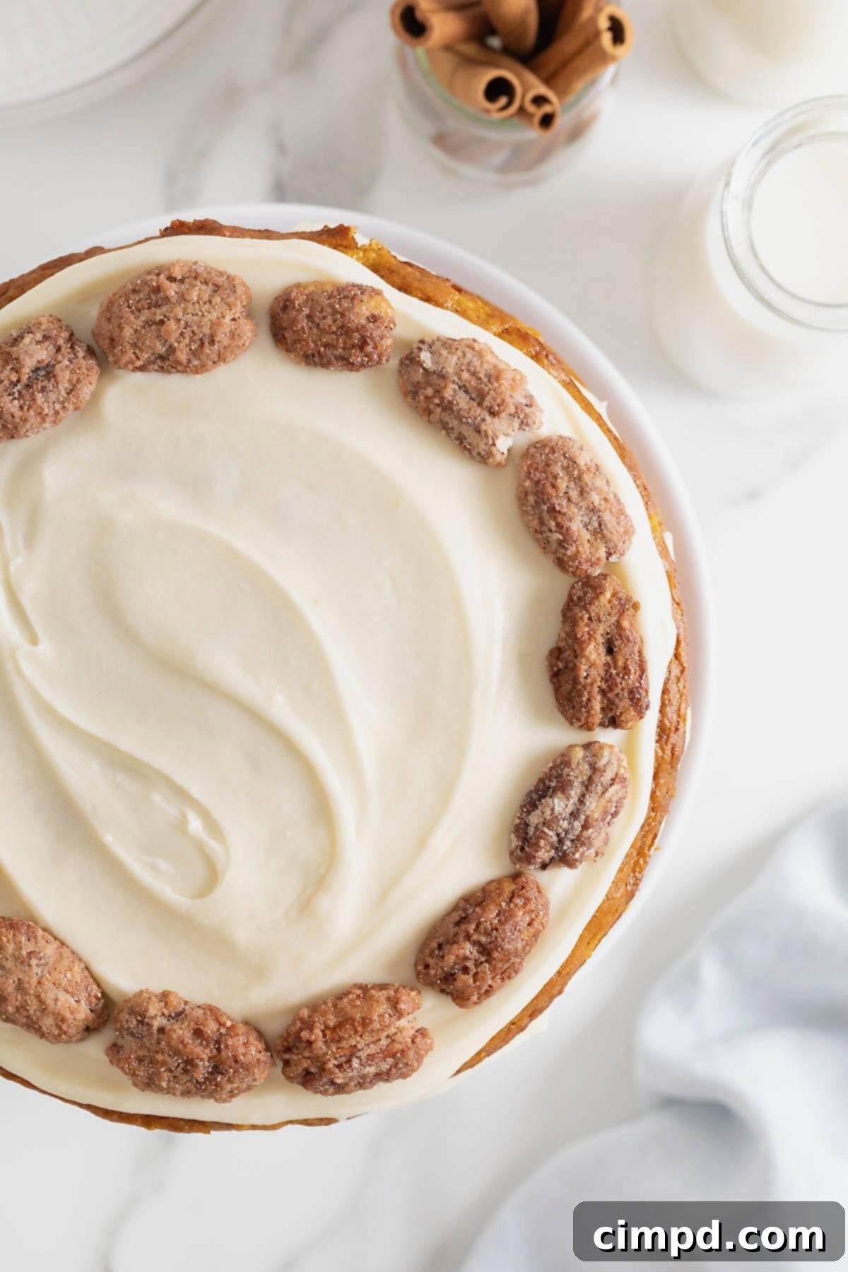The overhead view of a perfectly frosted cake, adorned with a delicate ring of candied pecans, showcasing its inviting texture.