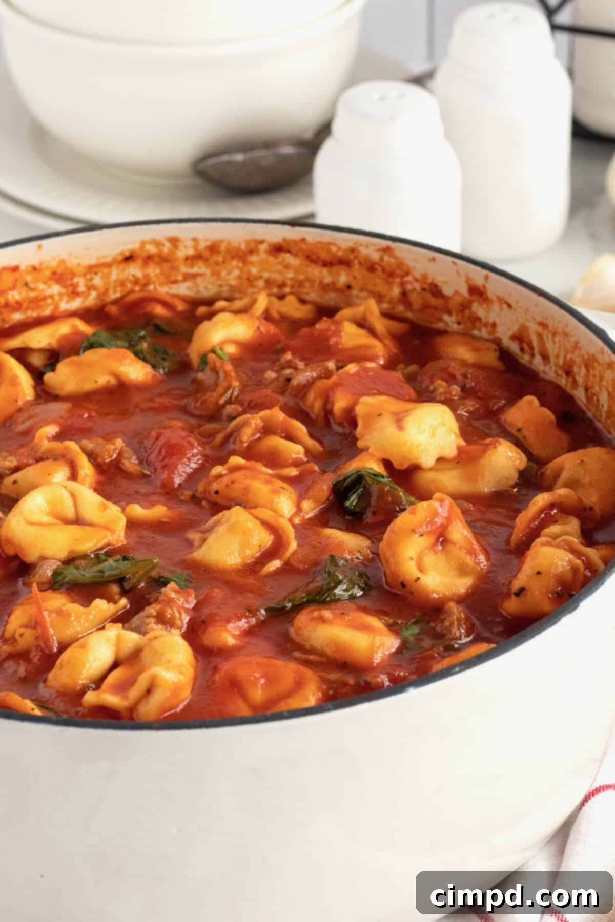 A large white dutch oven filled with tortellini soup.