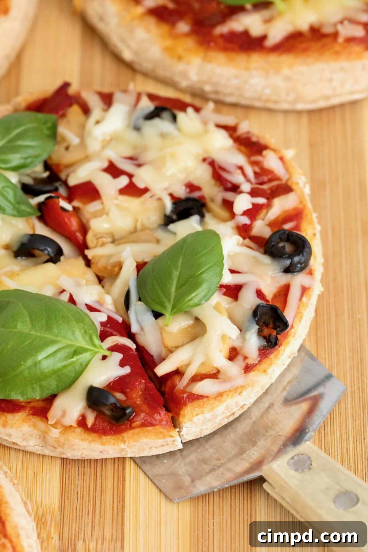 A personal size pizza with a golden whole wheat Greek yogurt crust topped with fresh basil and shredded white cheese on a rustic wooden cutting board.