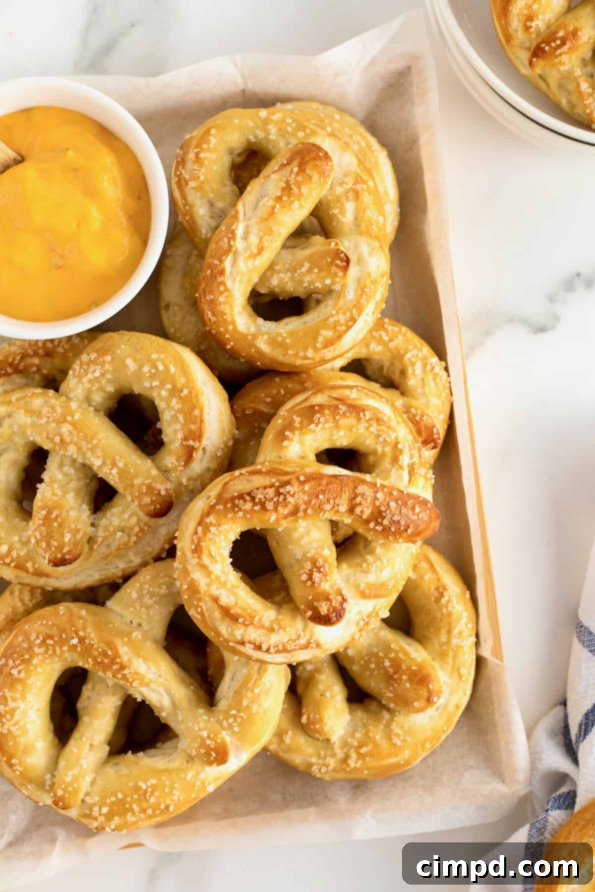 A wooden tray filled with soft pretzels and a small dish of cheese sauce.