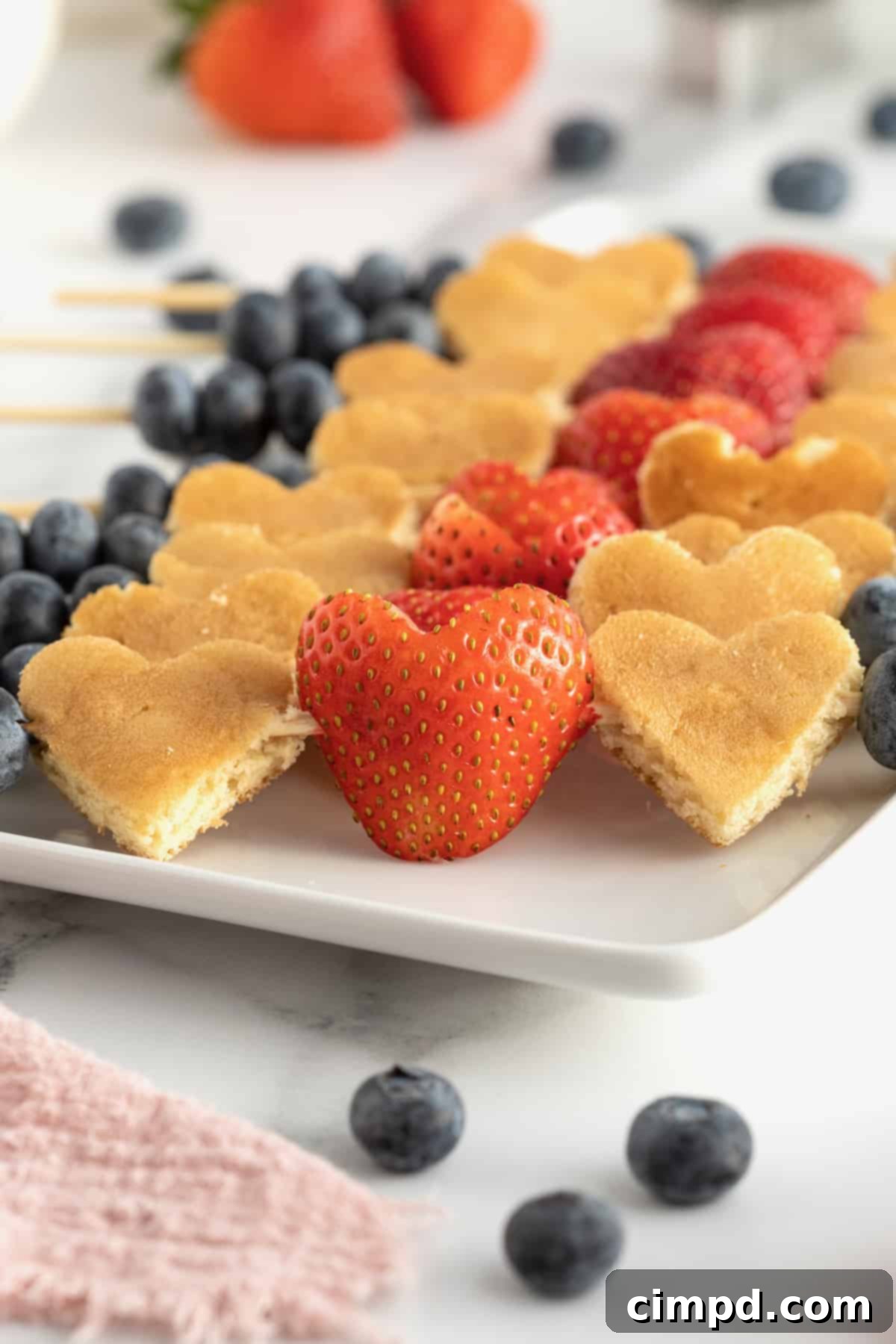 Cupid's Pancake Skewers 4 Hand holding a Cupid's Pancake Kabob with heart pancakes and strawberries
