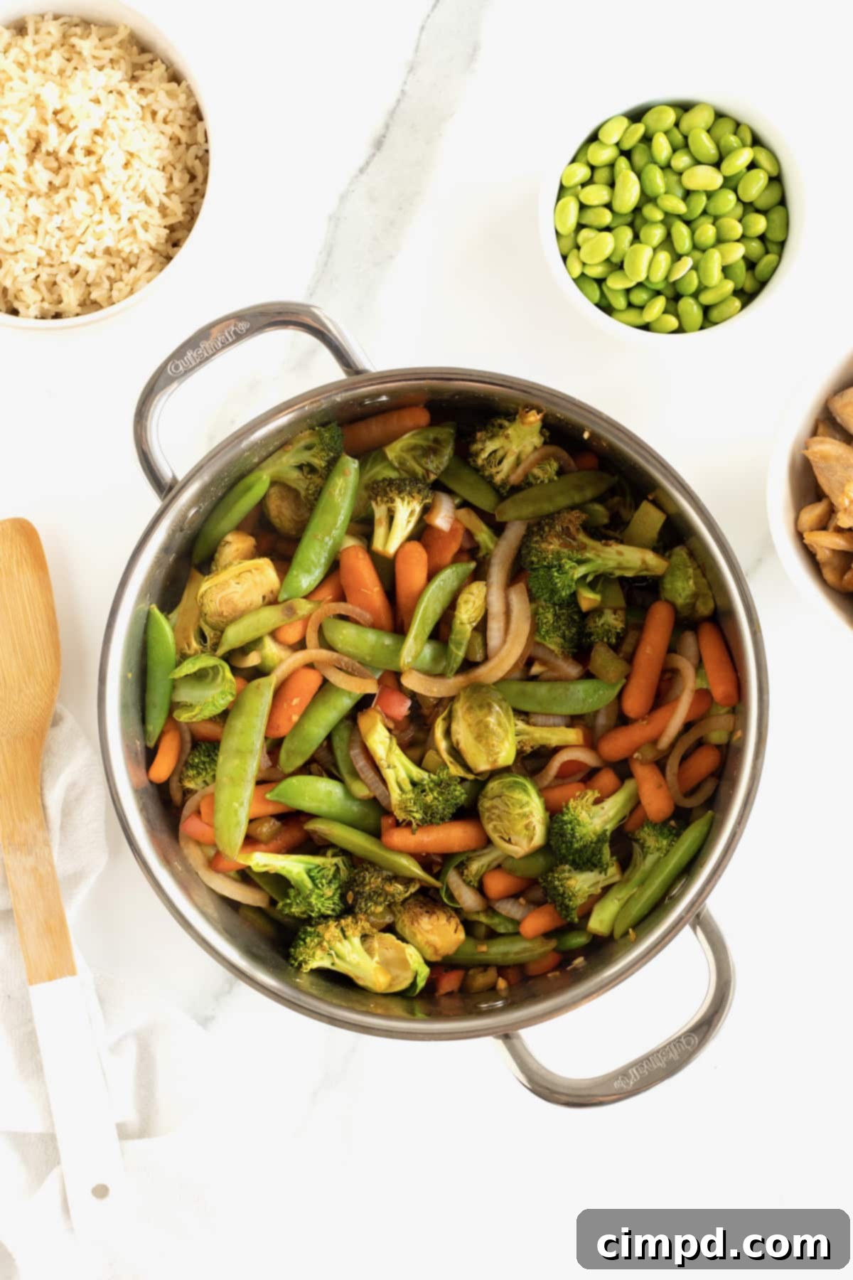 A close-up shot of vibrant mixed vegetables and cooked chicken sizzling in a wok, perfectly coated in the rich stir-fry sauce during the cooking process.