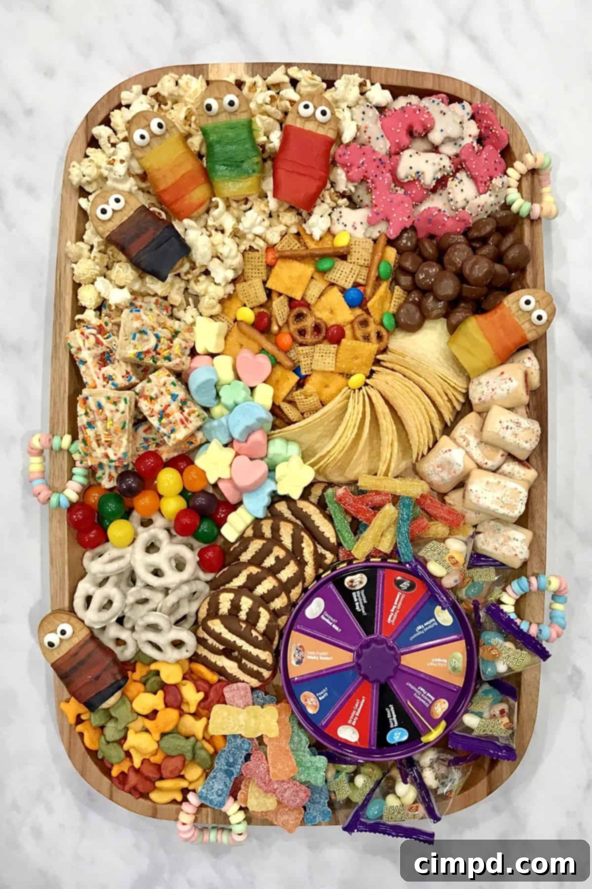 A beautifully arranged Slumber Party Snack Board featuring a variety of colorful candies, cookies, popcorn, and a Bean Boozled game, set against a cozy background.