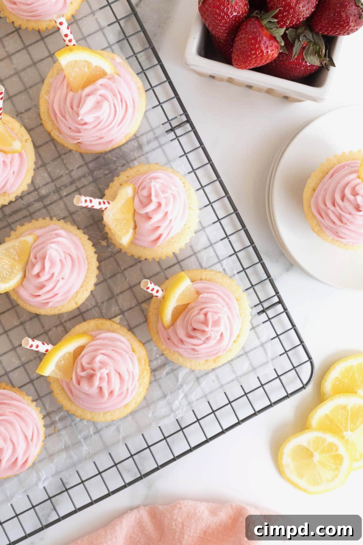 Freshly baked strawberry lemonade cupcakes gracefully cooling on a parchment-lined wire rack, showcasing their perfect golden-brown tops.