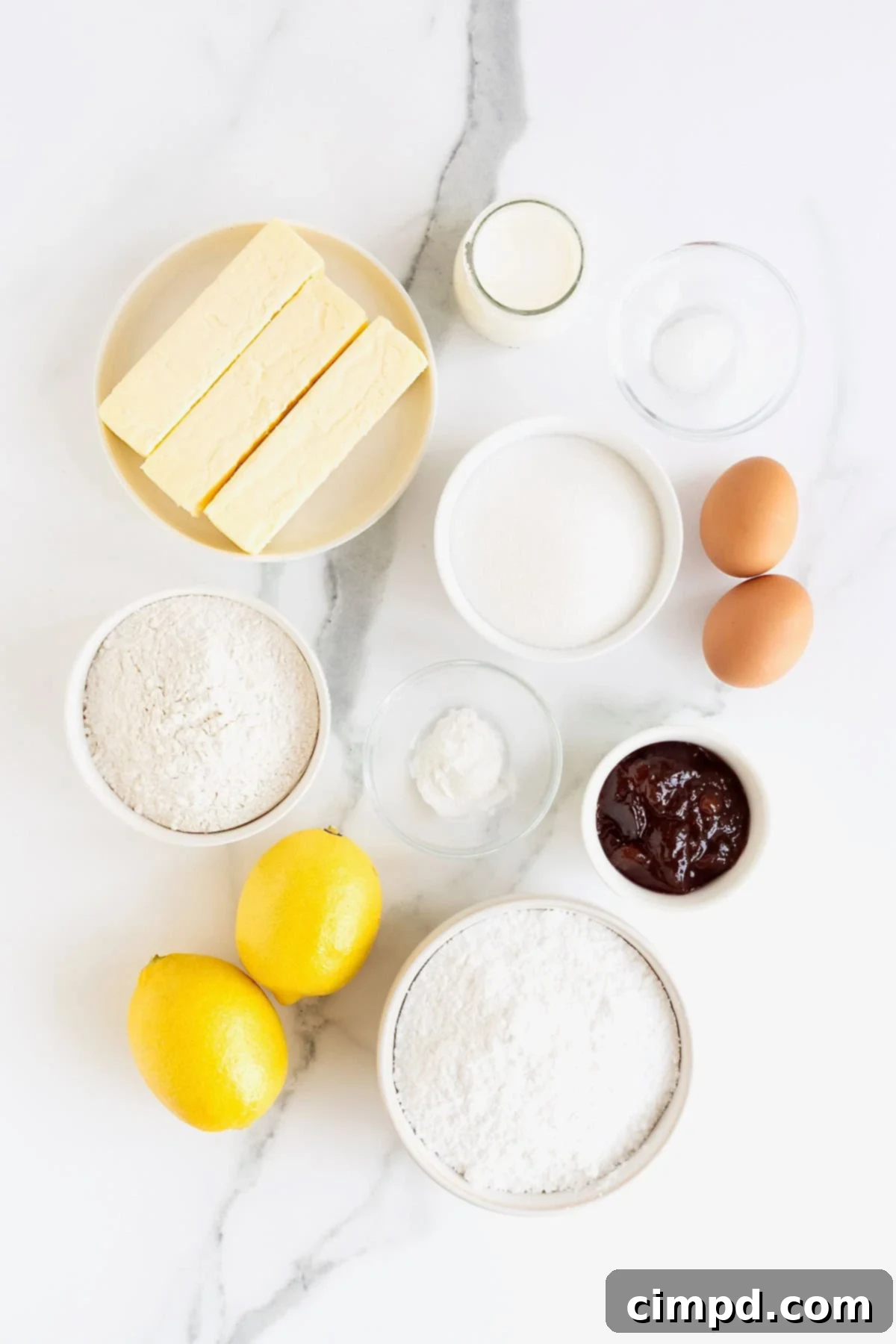 Ingredients to make strawberry lemonade cupcakes meticulously arranged in small glass dishes on a pristine white marble counter, ready for baking.