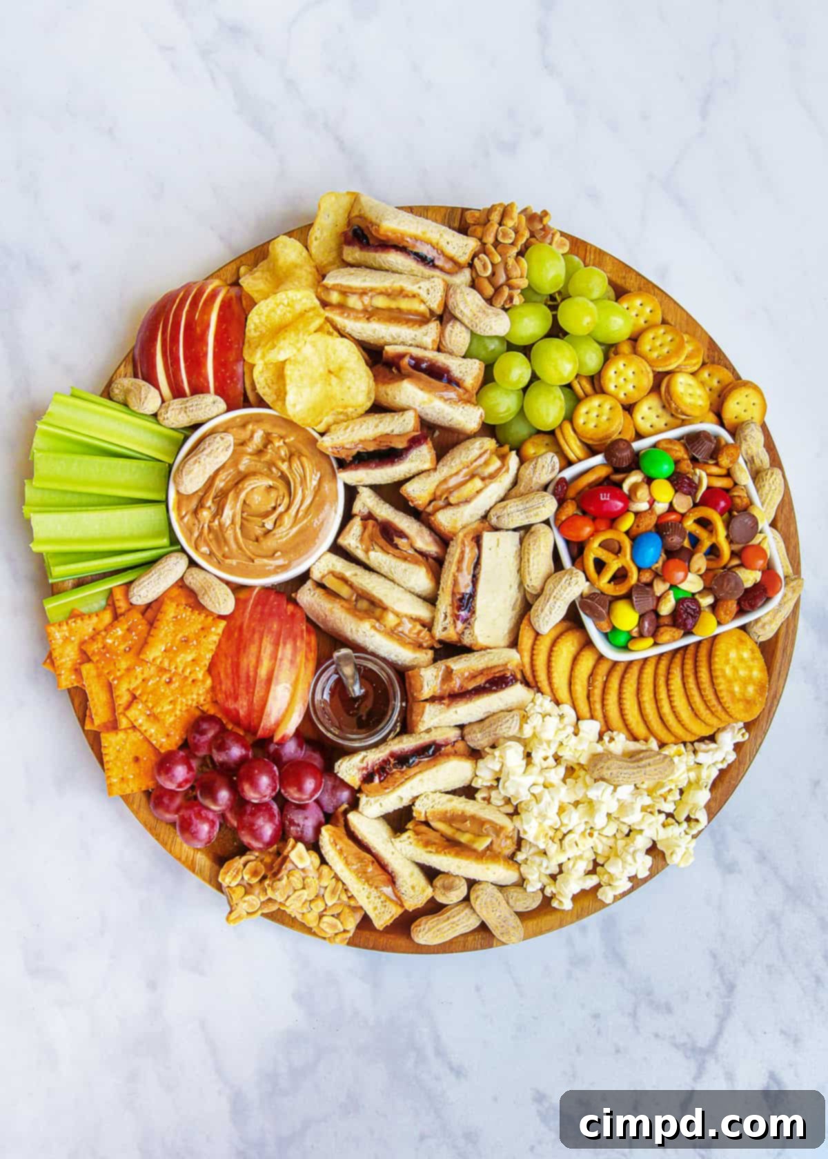 A beautifully arranged PB&J Snack Board with sandwiches, fruits, and various snacks.