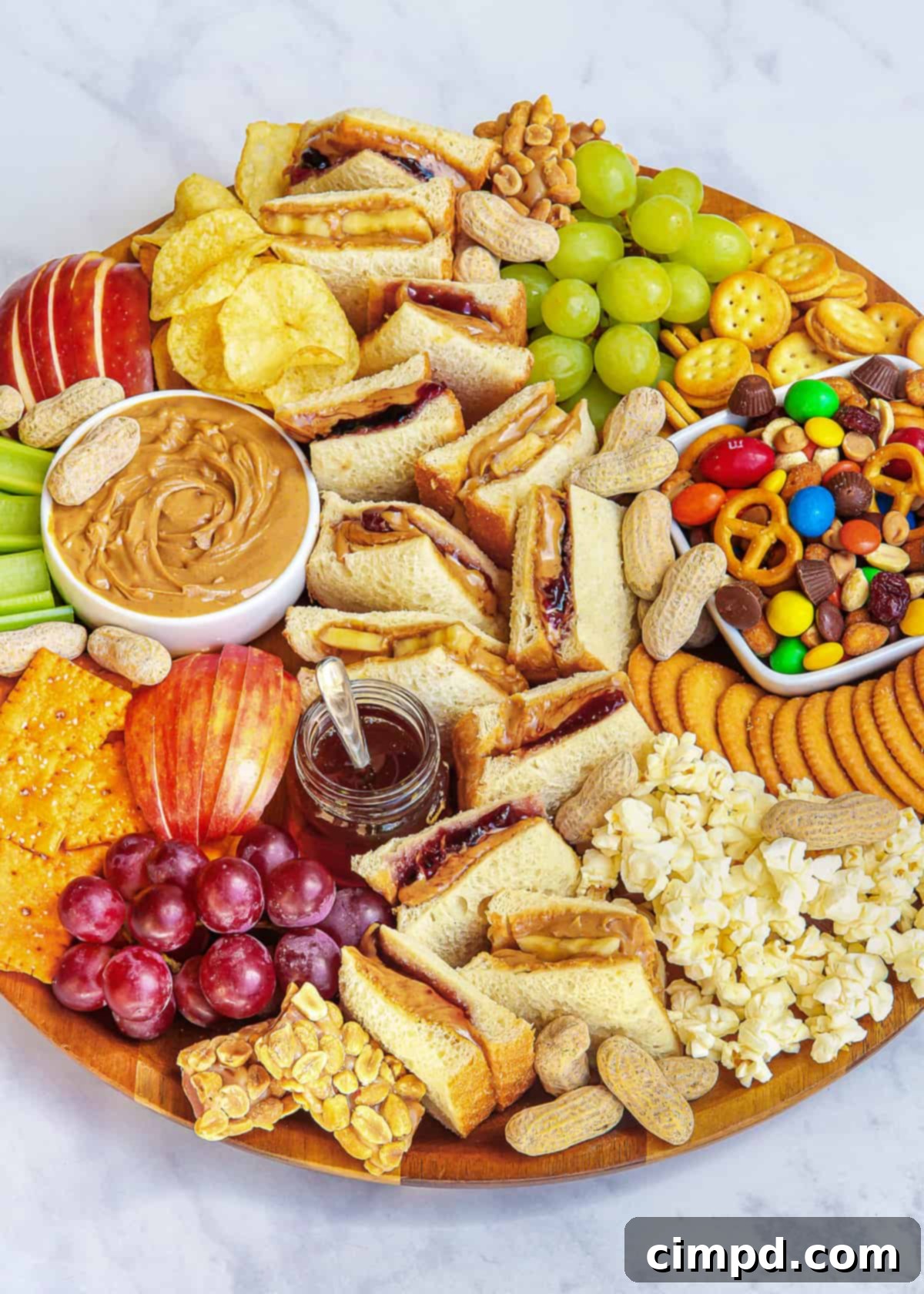 Close-up of a PB&J Snack Board featuring a variety of jellies, fruit, and crackers.
