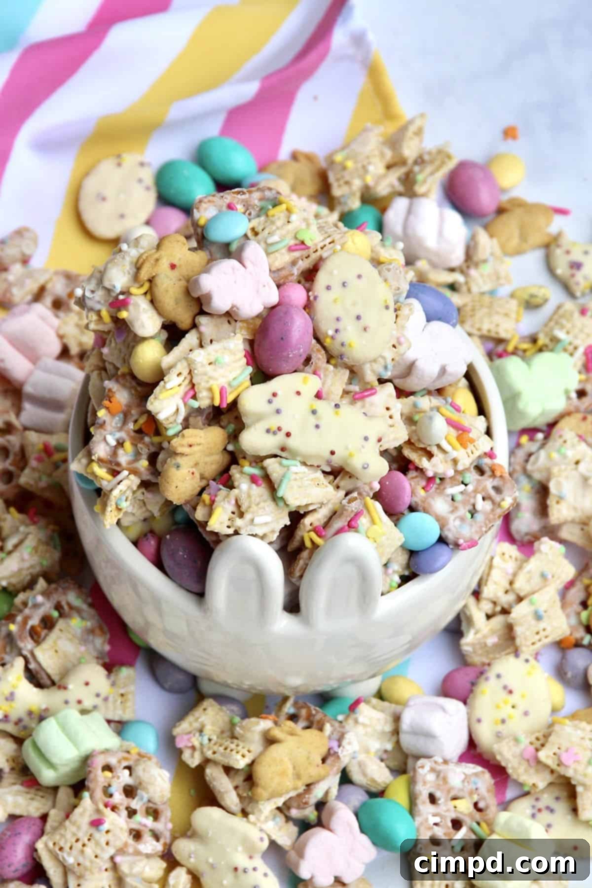 Hoppy Easter Munch 4 Easter Snack Mix ingredients arranged on a surface, featuring cereals, pretzels, candies, and bunny-themed items.