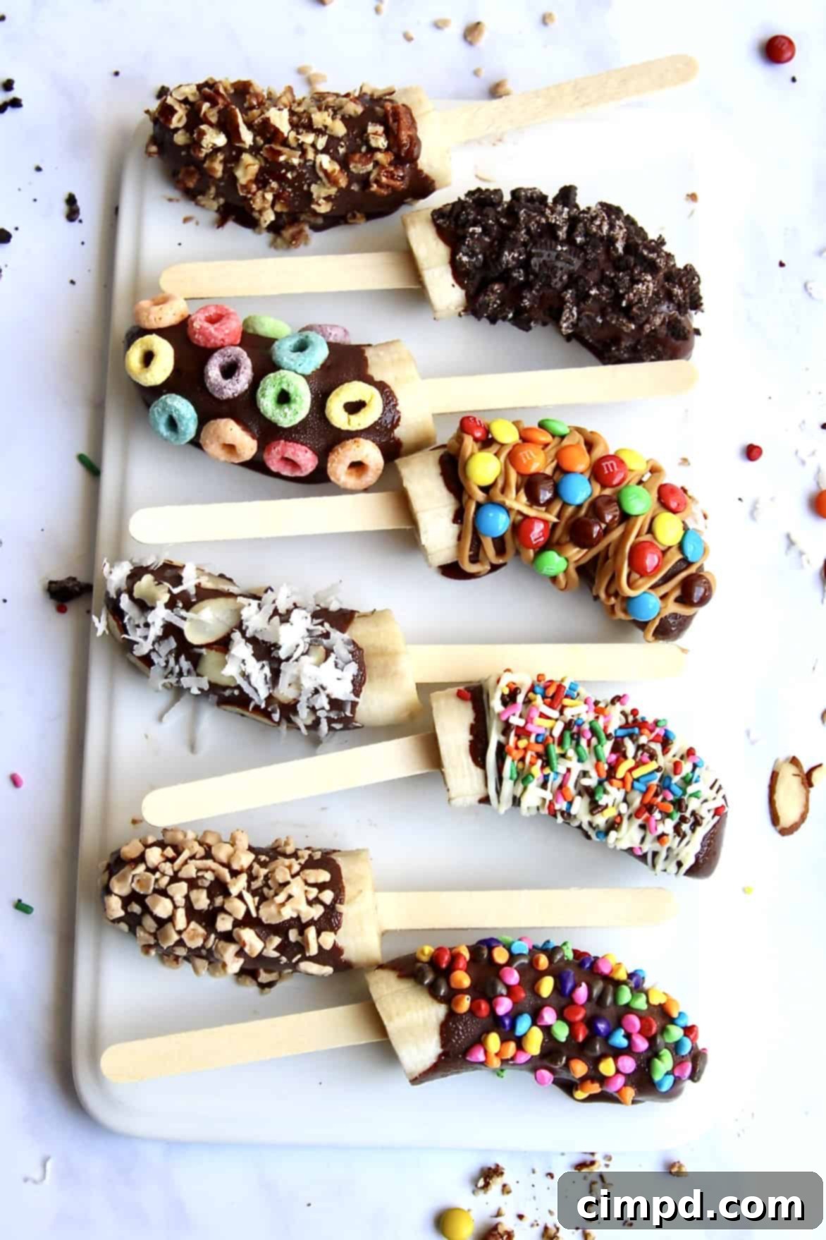Variety of chocolate covered frozen banana pops with different toppings