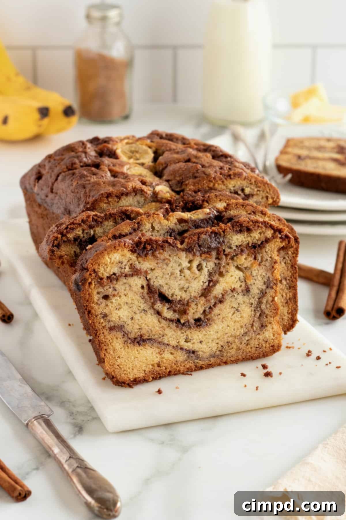 Golden brown cinnamon swirled banana bread loaf cooling on a wire rack.