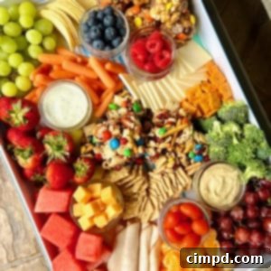 Picnic Perfection Platter 8 A white snack tray filled with fruits, cheeses, popcorn balls and snack bars.