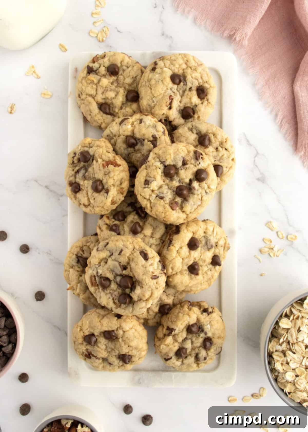 A batch of golden brown Coconut Pecan Chocolate Chip Oatmeal Cookies cooling on parchment paper