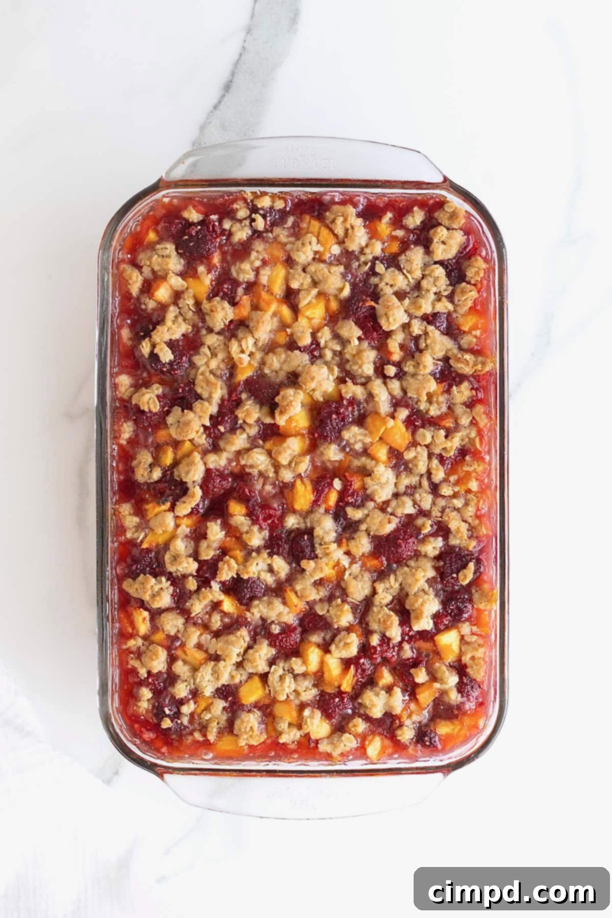 Golden Peach Raspberry Crumble Squares 10 A close-up shot of a glass baking dish brimming with freshly baked and cooled peach raspberry crumb bars, featuring their enticing golden crusts.