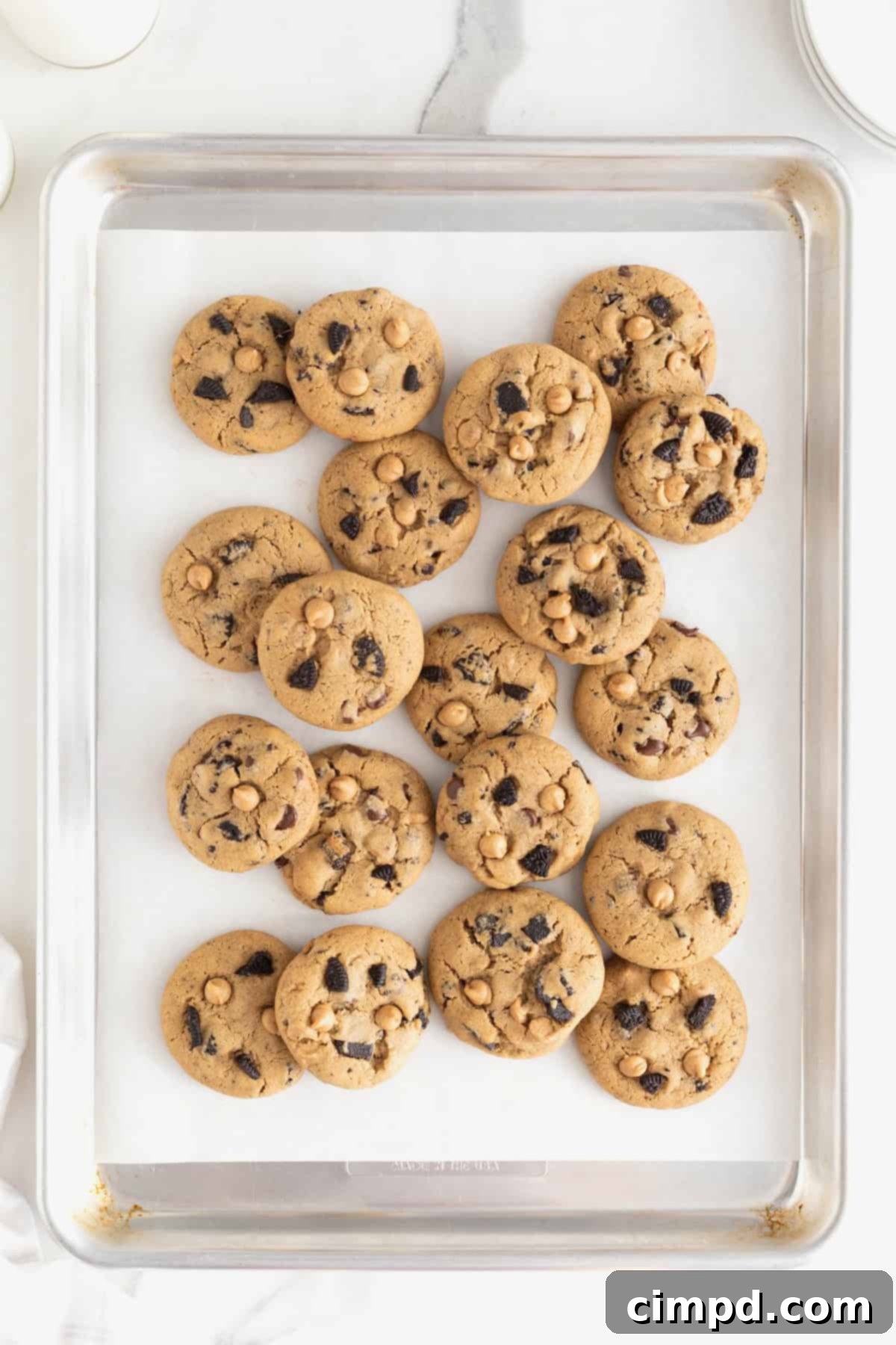A pile of peanut butter Oreo cookies on a parchment lined cookie sheet, showcasing their rich texture.