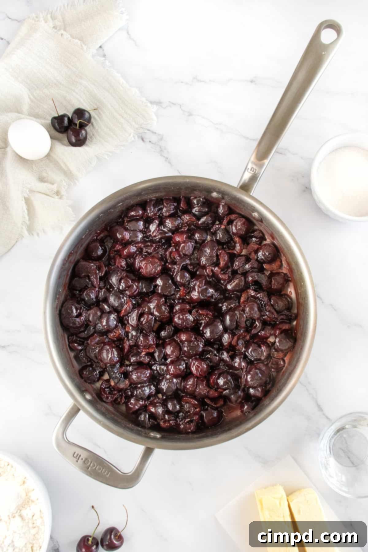 Cooked cherries in a metal saucepan.