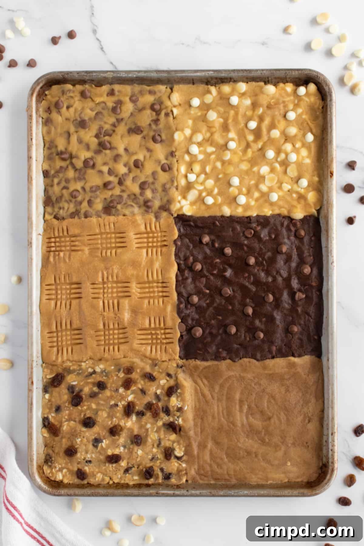 A close-up of the sheet pan with all six cookie dough sections garnished with their respective toppings, showcasing the visual appeal before baking.