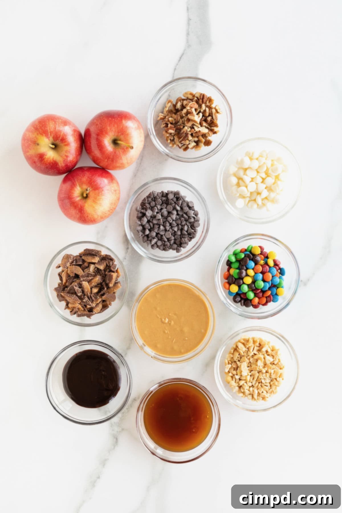 Loaded Apple Slices 5 Ingredients to make apple nachos in small glass dishes on a white marble counter.