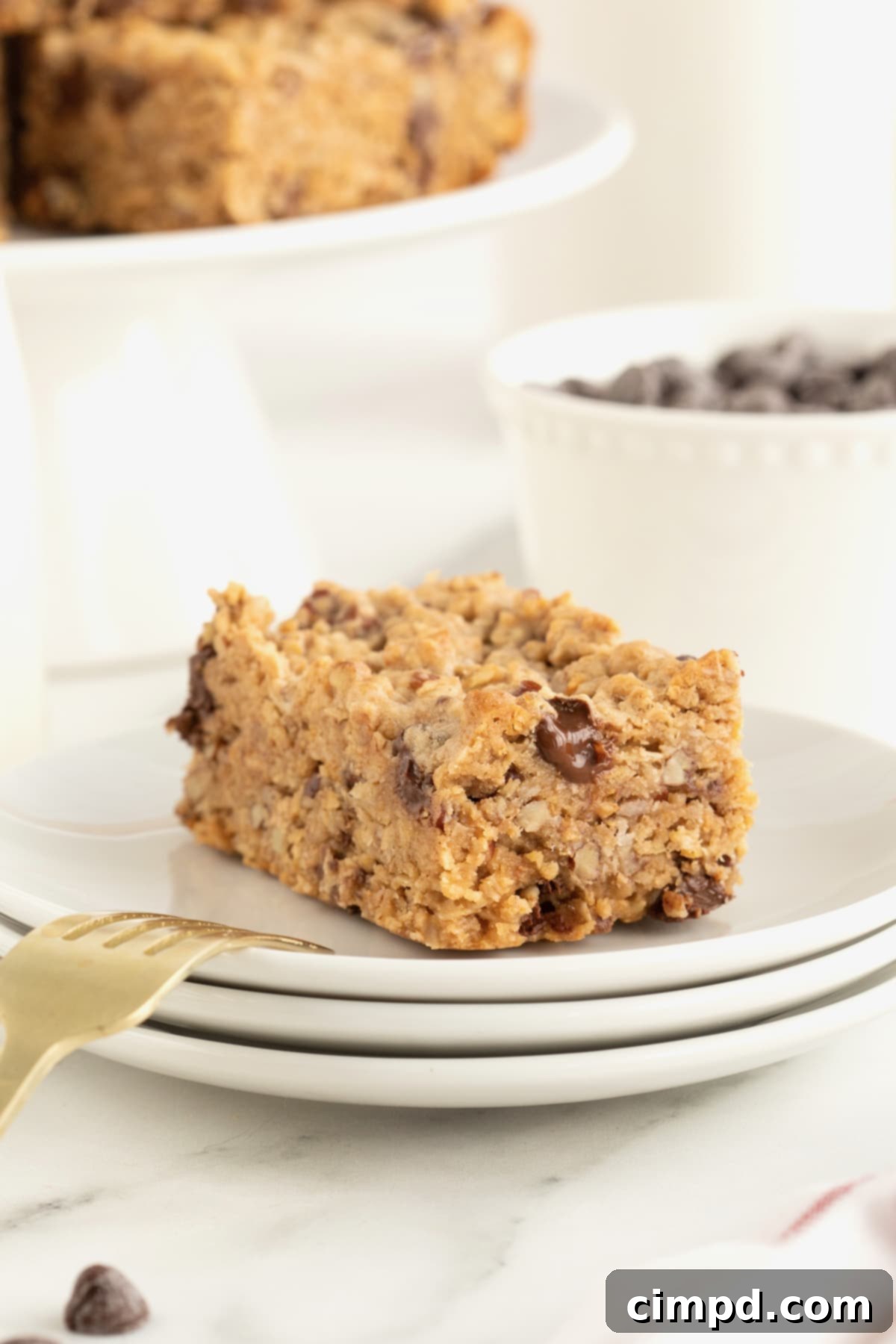 Homemade Chocolate Chip Granola Bars 4 A granola bar with chocolate chips on a plate with a gold toned fork resting on the plate.