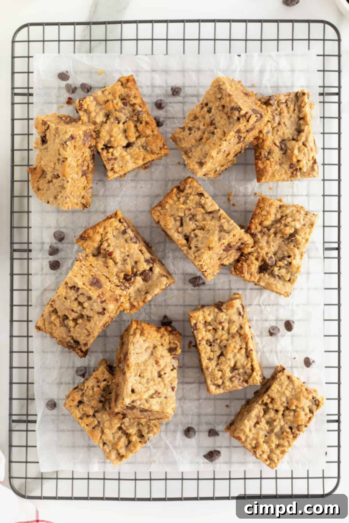 Homemade Chocolate Chip Granola Bars 5 Individual granola bars on a parchment lined metal cooling rack with chocolate chips scattered around them.