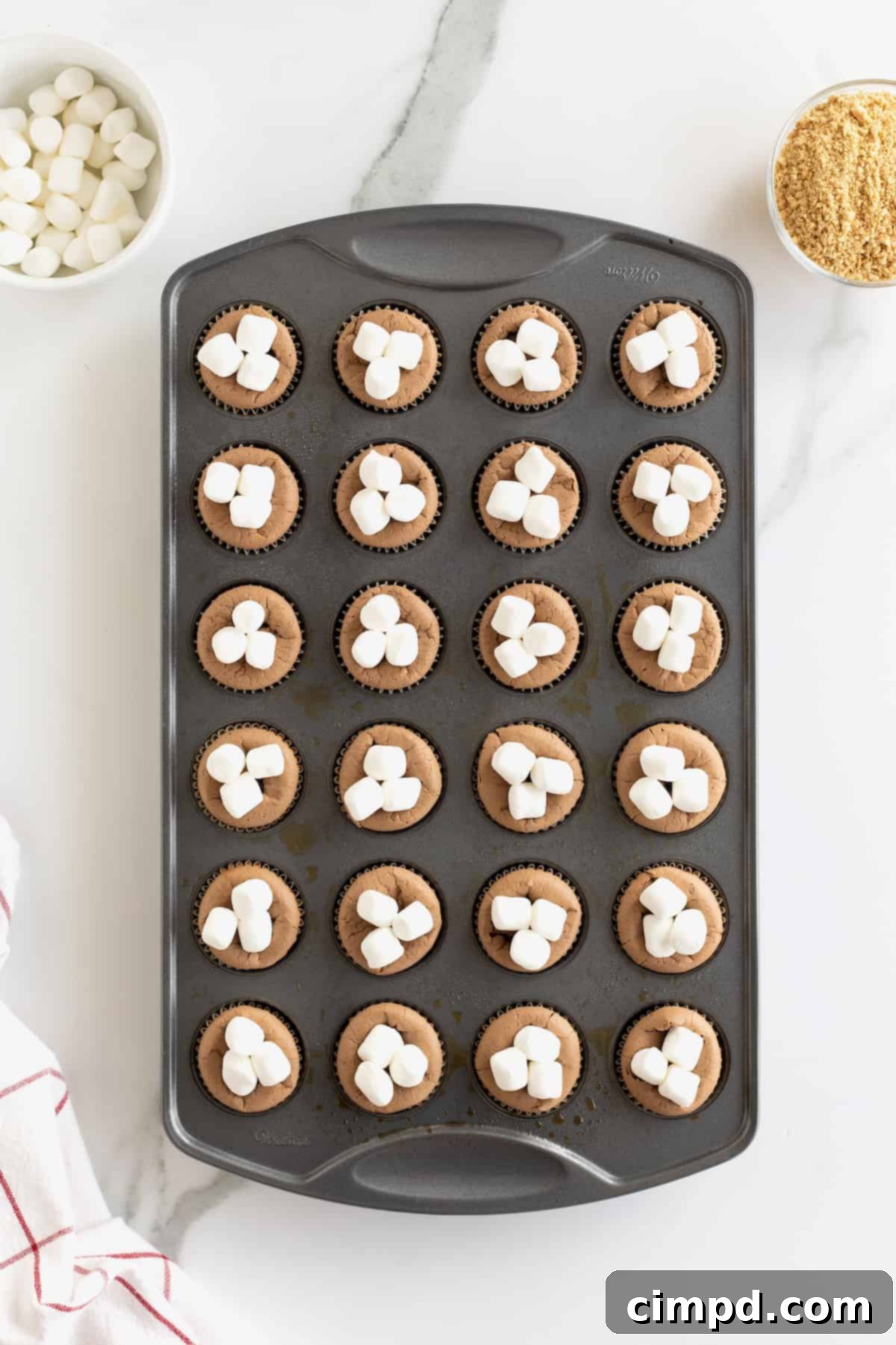 Three mini marshmallows on top of mini chocolate cheesecakes.