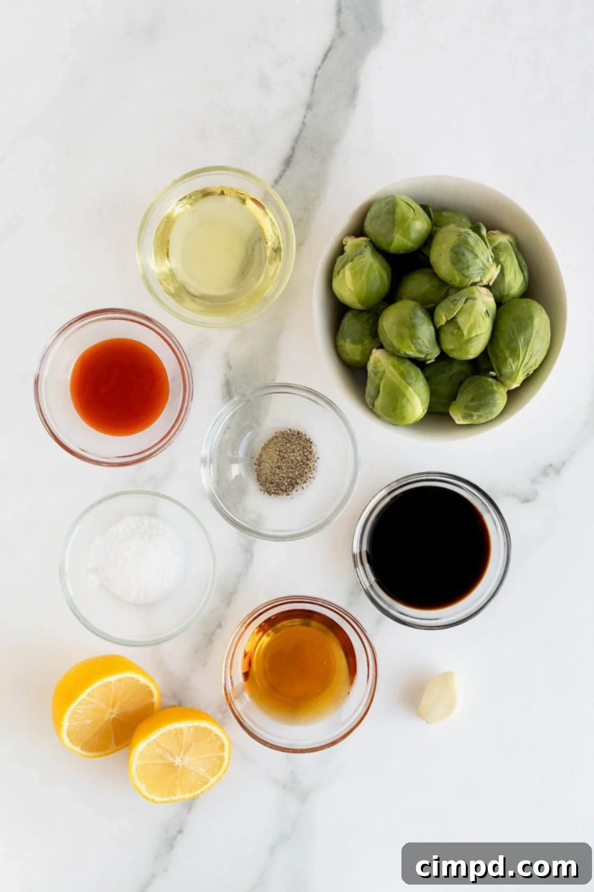 Ingredients for Crispy Asian Brussels Sprouts in small glass dishes on a white marble counter, ready for preparation.