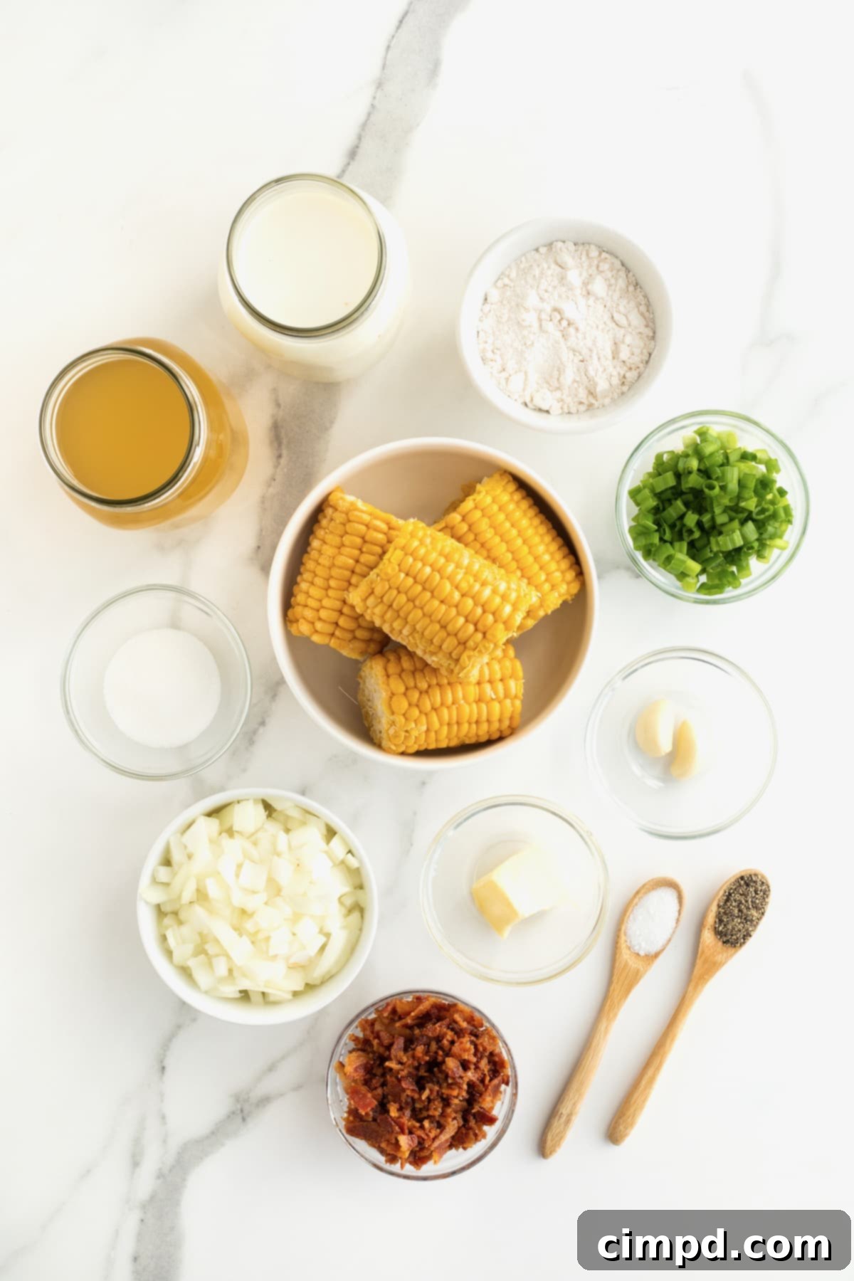 Various ingredients for corn chowder meticulously arranged in small glass dishes on a pristine white marble counter, showcasing freshness and readiness for cooking.