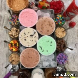 A dessert board feature ice cream sundae makings including ice cream, toppings, waffle bowls.