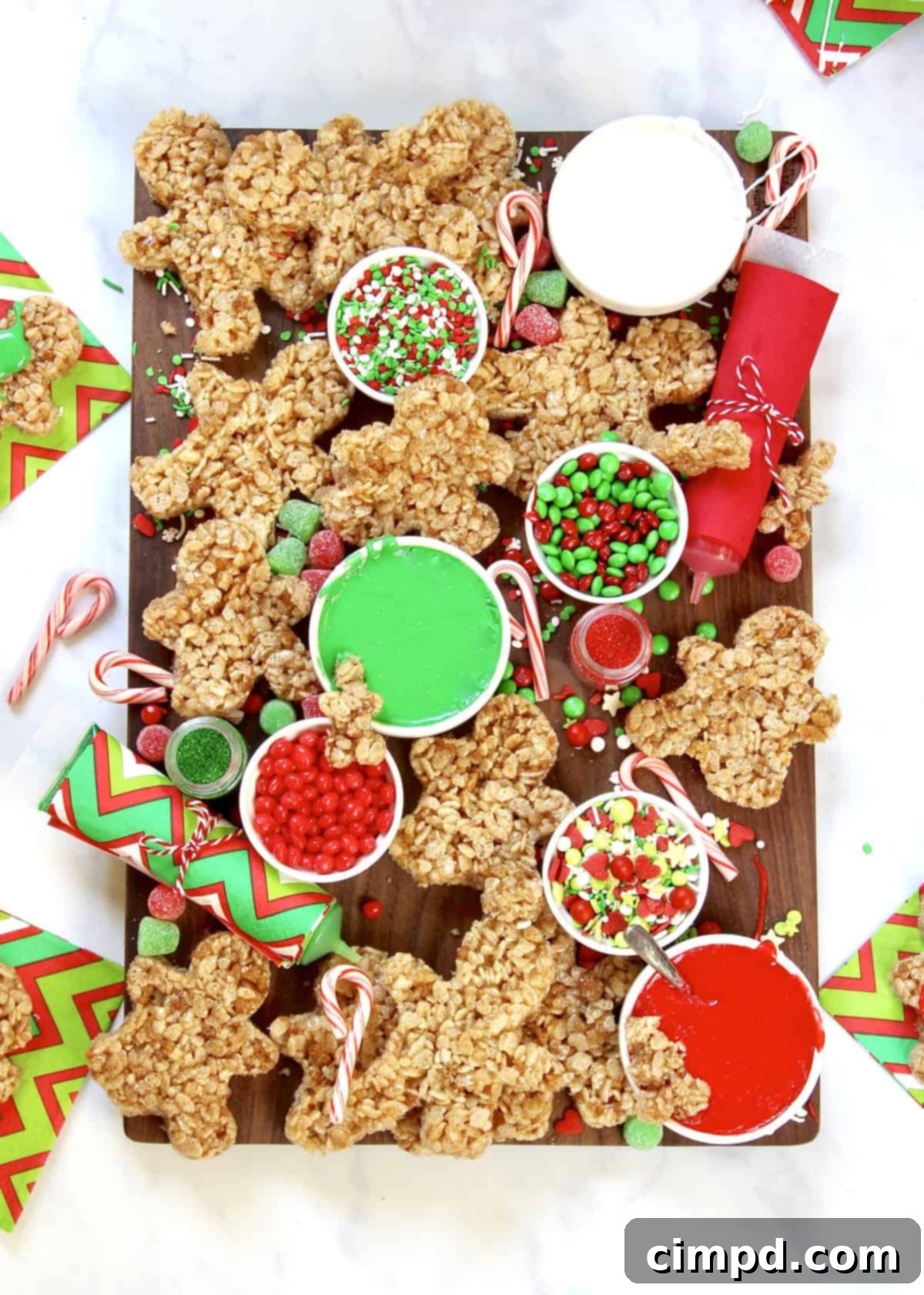 Hands decorating a no-bake gingerbread man on a festive board.