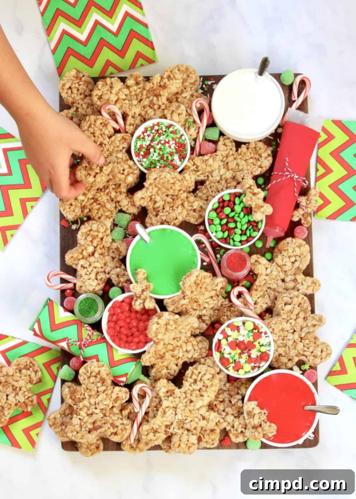 A child's hands decorating a gingerbread man with icing and sprinkles.